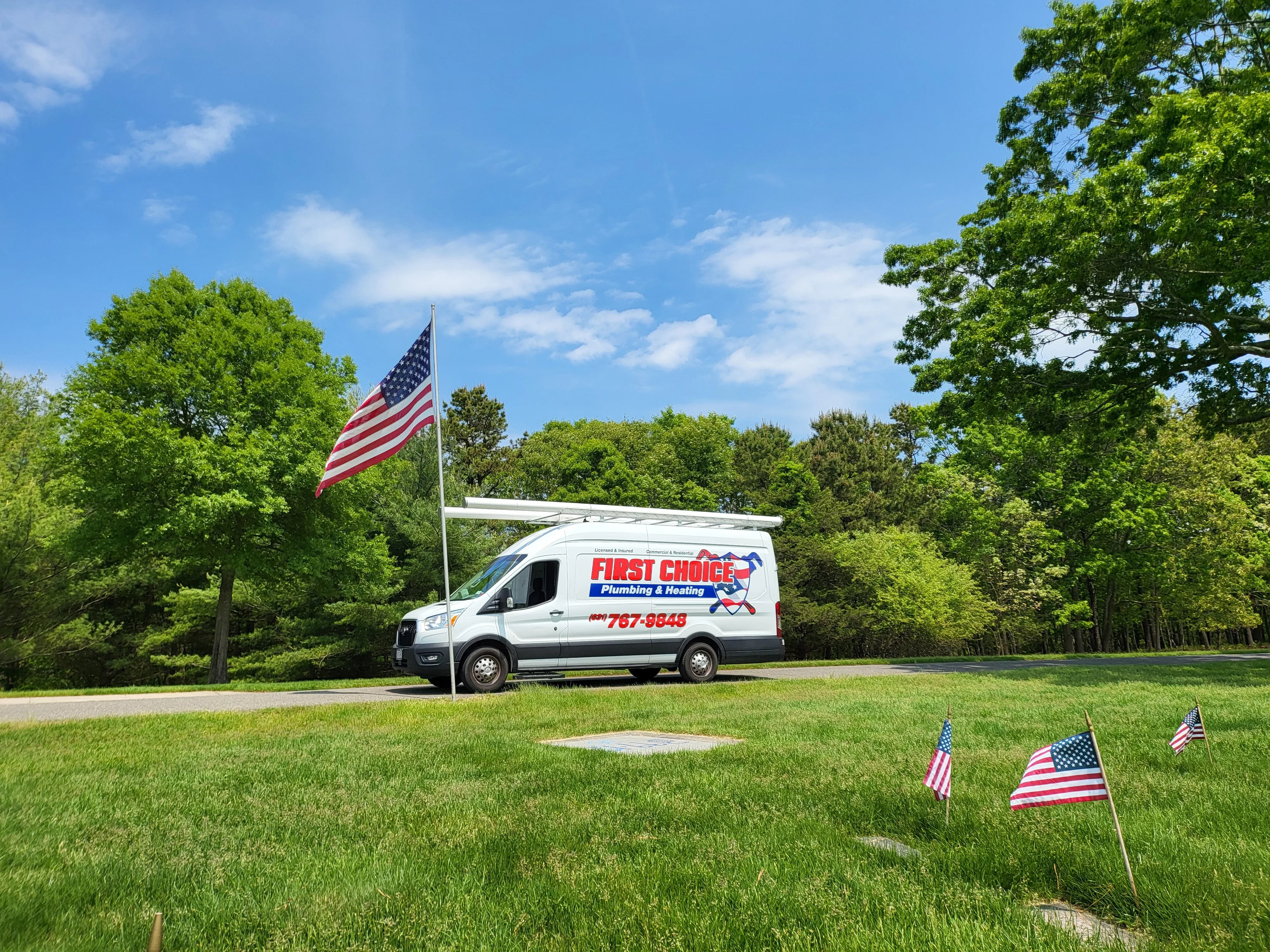 White service van with plumbing company branding and graphics parked on grass
