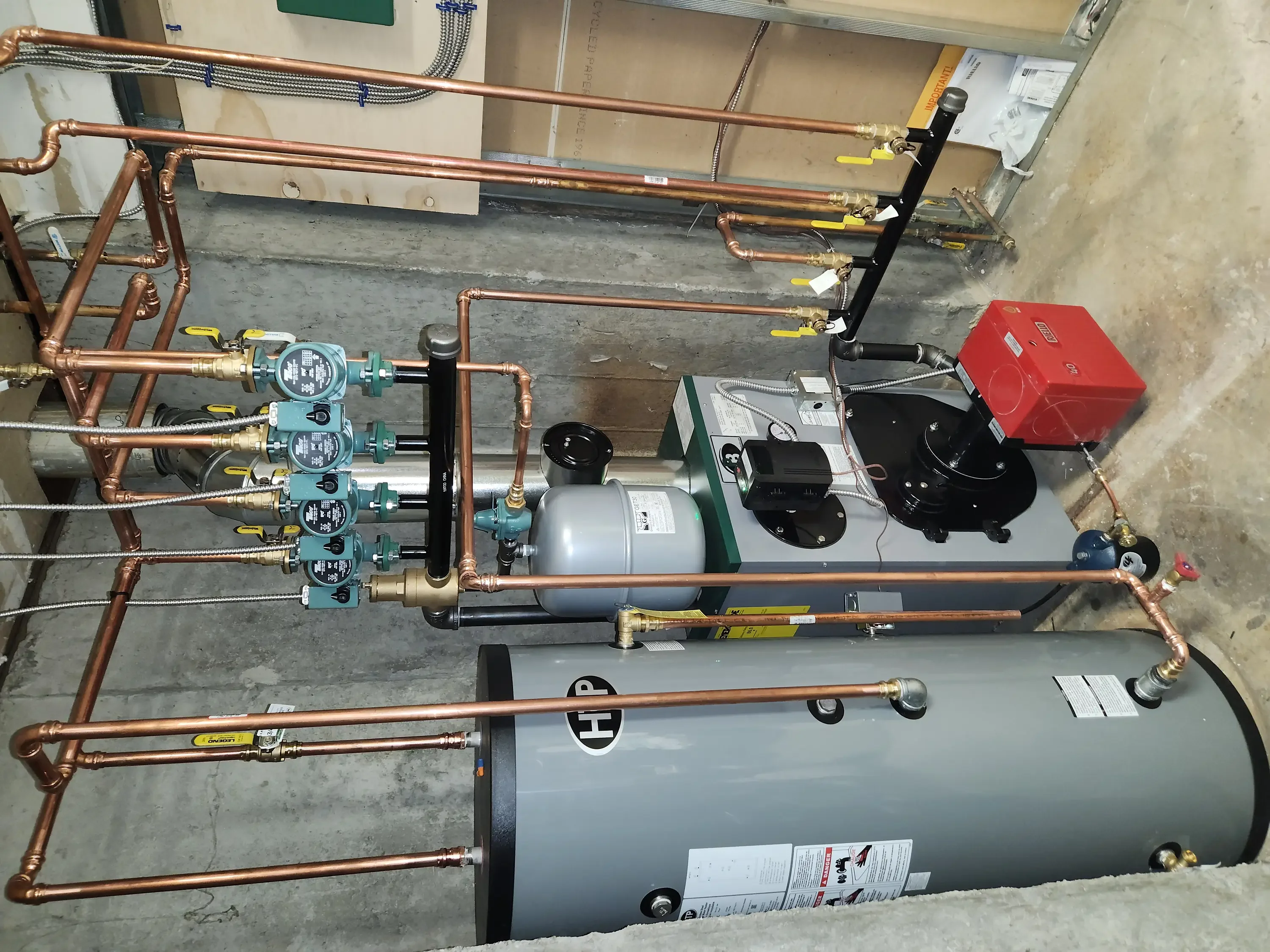 Copper radiant heating manifold with four zones, expansion tank, circulation pump, and brass fittings