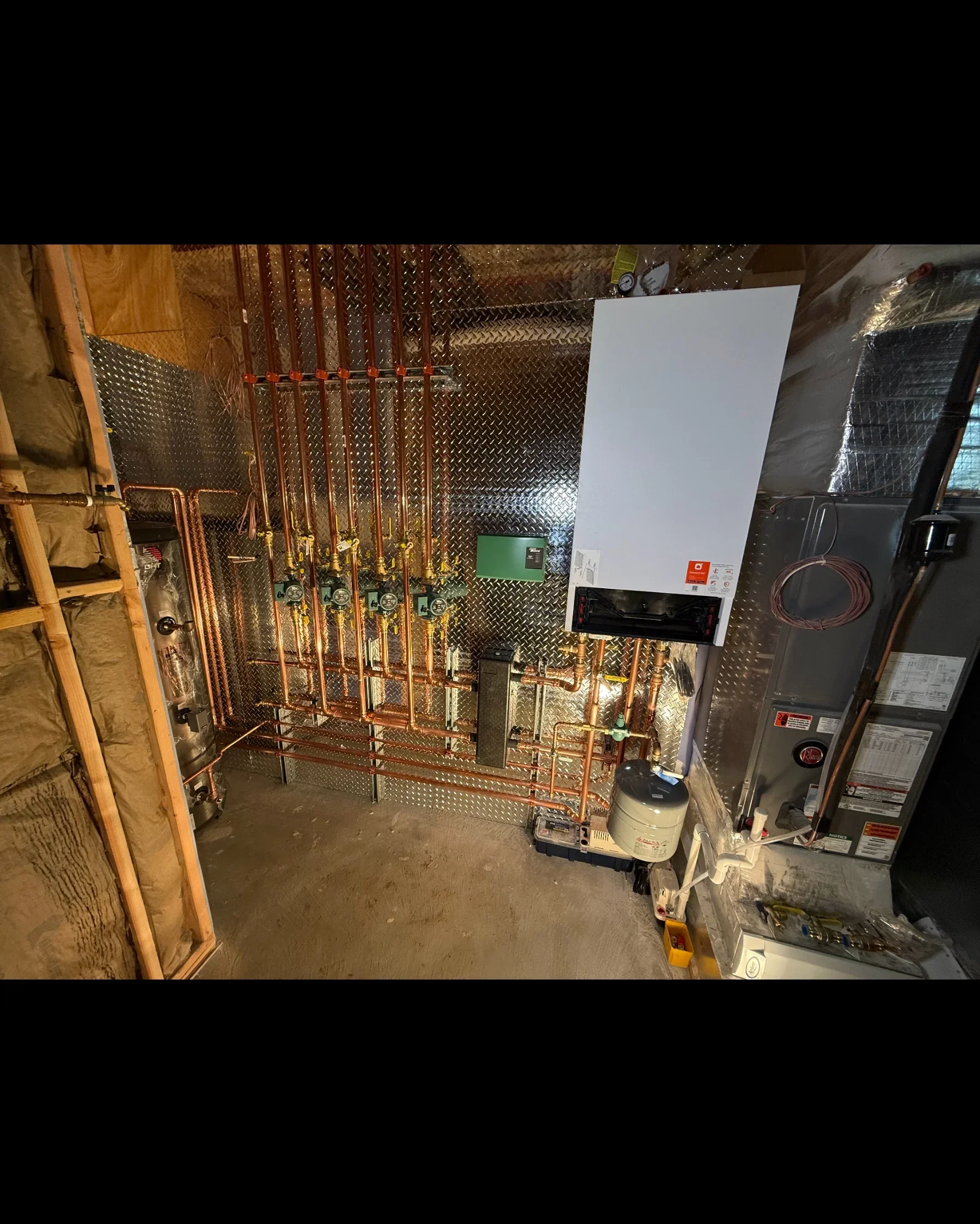 Copper radiant floor heating manifold with boiler, tubing, and expansion tank installation