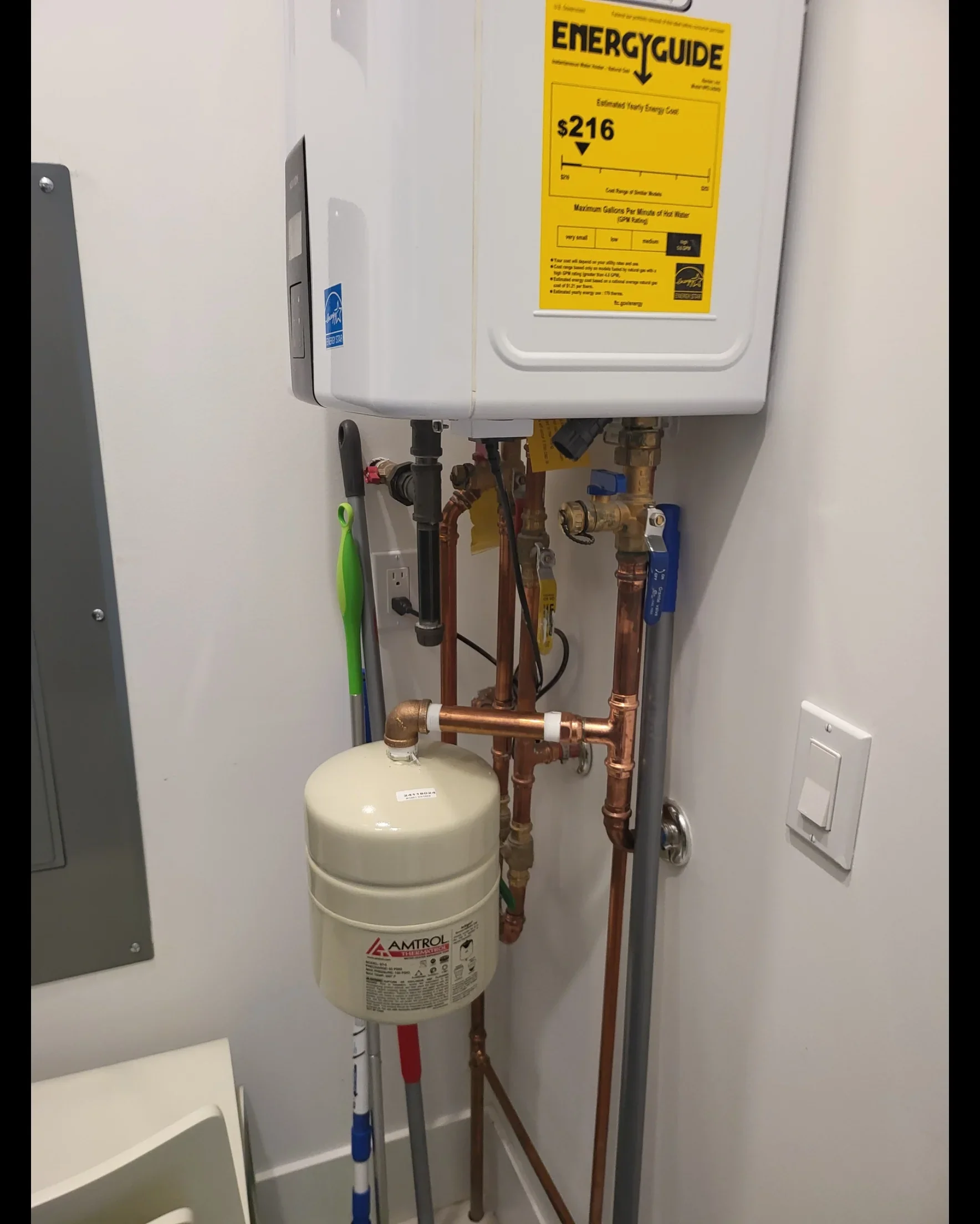 Tankless water heater with copper piping, expansion tank, and shut-off valves installed on wall